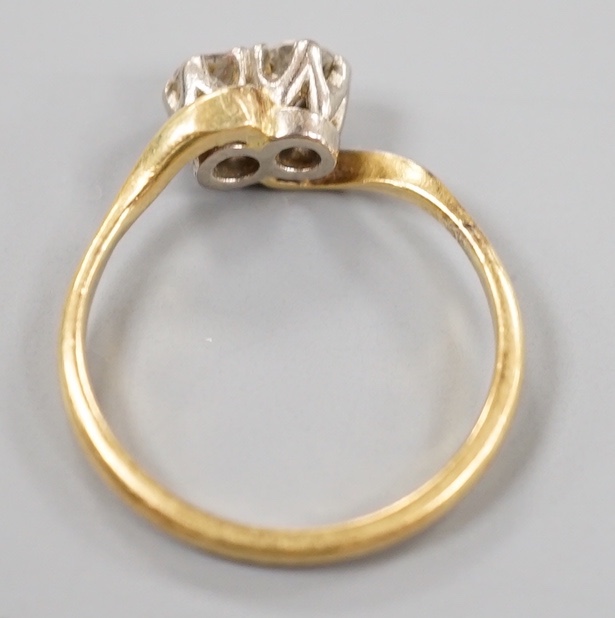 A yellow metal and plat, two stone diamond set crossover ring, size M, gross weight 2.8 grams.